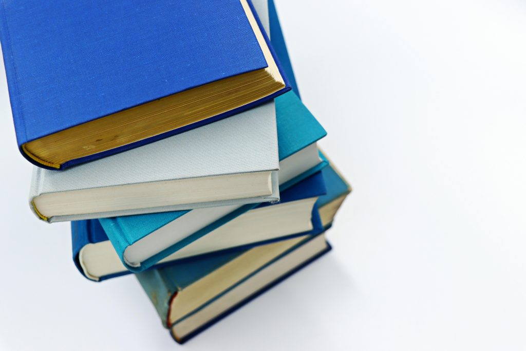 A vertical stack of books with blue covers on a white background symbolizes education and literature.